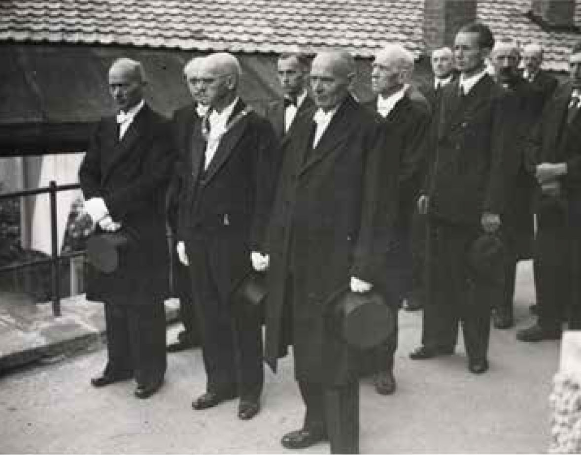 Mit Zylinderhut festlich gekleidete Repräsentanten der Stadt Miesbach, bei der Stadtpfarrkirche um 1950
